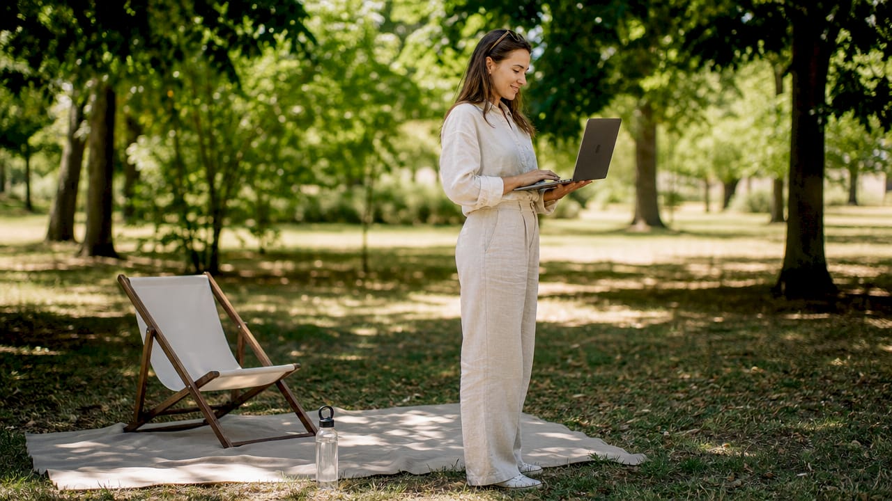 Une entrepreneuse installe son ordinateur portable sur la table d’un café, concentrée sur son travail.