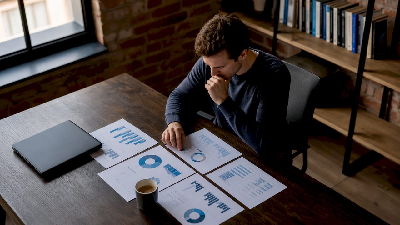 Un dirigeant de PME en pleine réflexion sur un projet de transformation digitale, examinant attentivement le dossier pour en évaluer les enjeux et les opportunités.